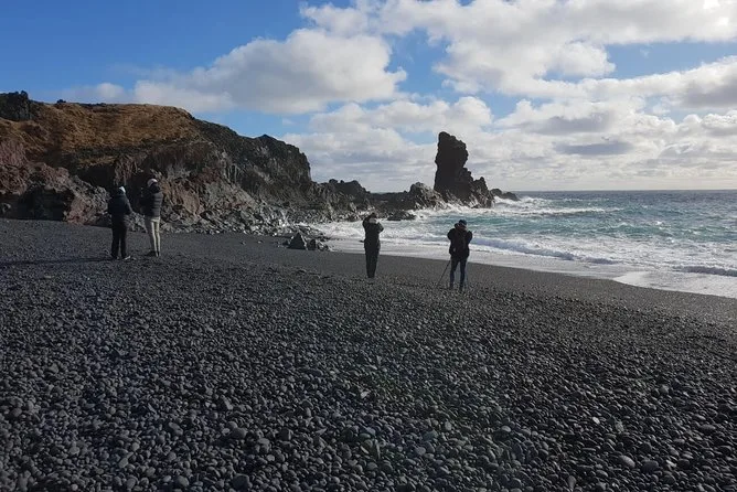 Besucher am schwarzen Kieselstrand Djúpalónssandur mit dunklen Felsnadeln und Brandung